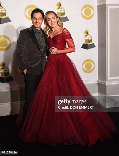 Fashion designer Zac Posen and singer Miley Cyrus pose in the press room during the 60th Annual Grammy Awards on January 28 in New York. / AFP PHOTO...