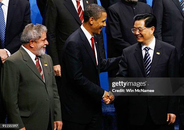 President Barack Obama shakes hands with Chinese President Hu Jintao as Brazilian President Luiz Inacio Lula da Silva looks on during a group photo...