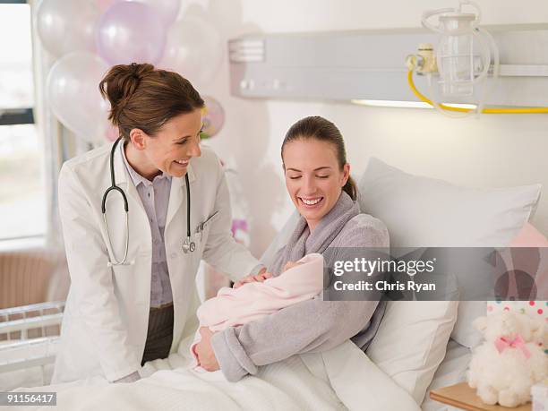 arzt vor frau holding neugeborenes baby im krankenhaus - strict parent stock-fotos und bilder