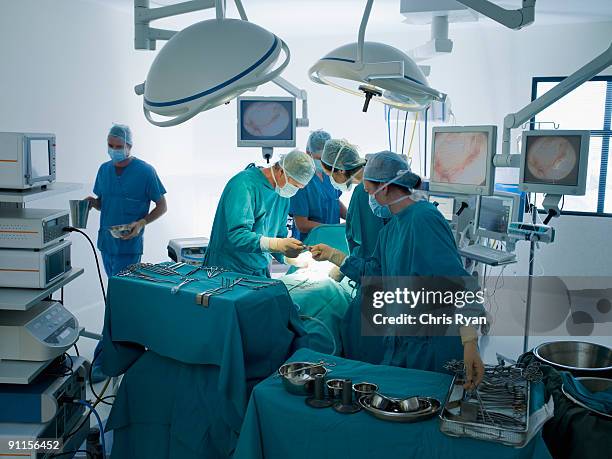 surgeons performing operation in operating room - operating theatre stock pictures, royalty-free photos & images
