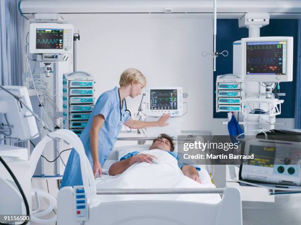 nurse tending patient in intensive care - medische apparatuur stockfoto's en -beelden