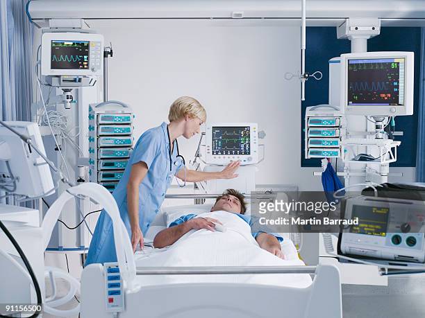 nurse tending patient in intensive care - intensive care unit stock pictures, royalty-free photos & images