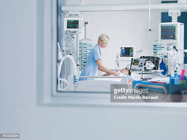 nurse tending patient in intensive care - intensive care unit stock pictures, royalty-free photos & images