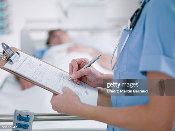 enfermera tending paciente en la unidad de cuidados intensivos - clipboard fotografías e imágenes de stock