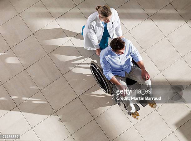 doctor pushing man in wheelchair - wheelchair stock pictures, royalty-free photos & images