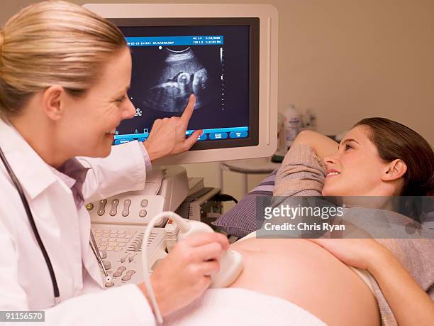 woman looking at ultrasound results with doctor - prenatal care stock pictures, royalty-free photos & images