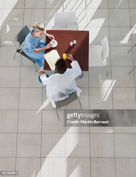 doctor and nurse talking in cafeteria - lunchpauze stockfoto's en -beelden