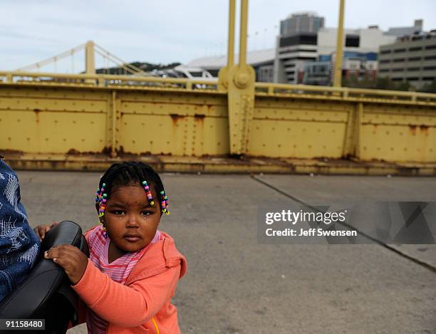 Small girl rides on the back of her mother's wheelchair as police force away them and a group of protesters marching across the 7th St Bridge in...