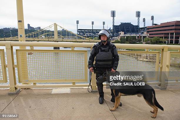 Police officer dressed in riot gear along with his guard dog watch as thousands of demonstrators march through downtown Pittsburgh, Pennsylvania, on...
