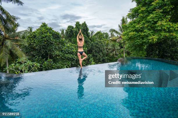 jonge vrouw stond aan de rand van een infinity pool, ubud, bali - indonesia women stockfoto's en -beelden