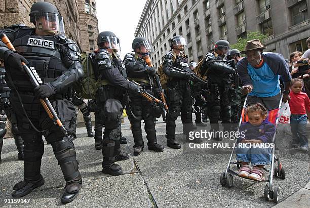 Man walks two young girls as police in riot gear guard the streets during protests in Pittsburgh, Pennsylvania, as world leaders attend the G20...