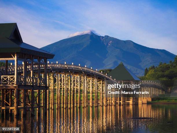 wooden arch bridge over lake with mountain and blue sky in the background - 東北地方 ストックフ�ォトと画像
