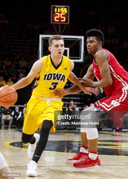 Guard Jordan Bohannon of the Iowa Hawkeyes brings the ball down the court during the first half in front of forward Aleem Ford of the Wisconsin...