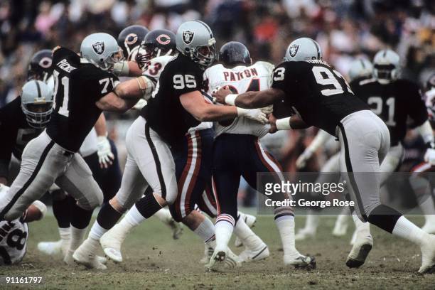 Bob Buczkowski and Greg Townsend of the Los Angeles Raiders tackle running back Walter Payton of the Chicago Bears during the game at the Los Angeles...
