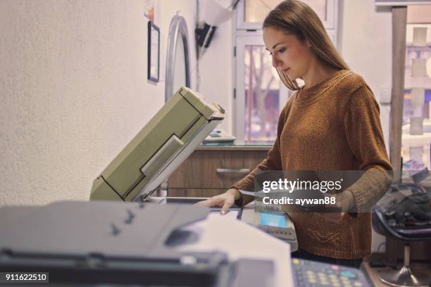 vrouw zetten van een vel papier in een apparaat voor kopiëren - printed media stockfoto's en -beelden