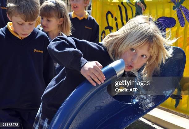 Schoolchildren queue to drink from a new public drinking fountain on the first day of a bottled water ban in the Southern Highlands community of...