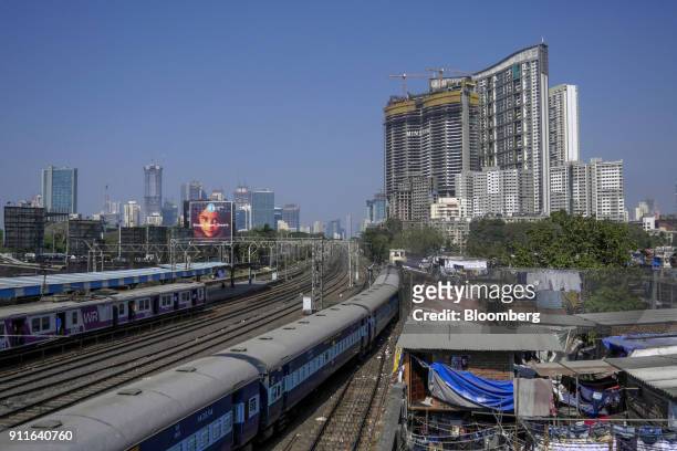 Train travels past slum housing as the under construction Minerva tower, developed by Lokhandwala Infrastructure Pvt., top right, stands in the...