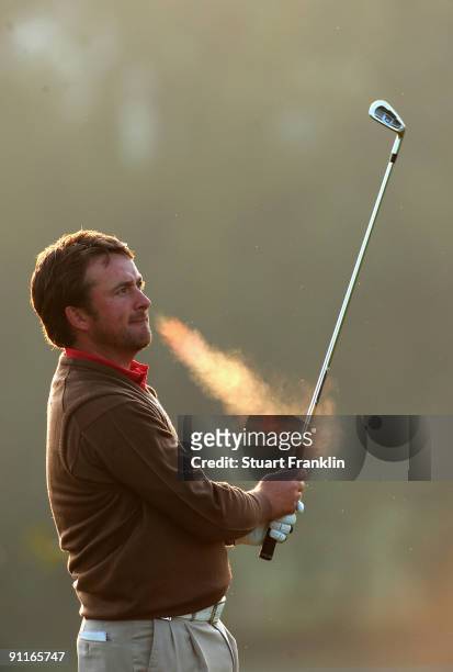 Graeme McDowell of the Great Britain and Northern Ireland team plays his approach shot on the first hole during the third day morning greensomes at...