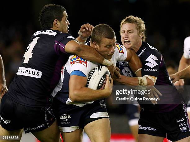 Ashton Sims of the Broncos is tackled by Greg Inglis and Brett Finch of the Storm during the second NRL Preliminary Final match between the Melbourne...