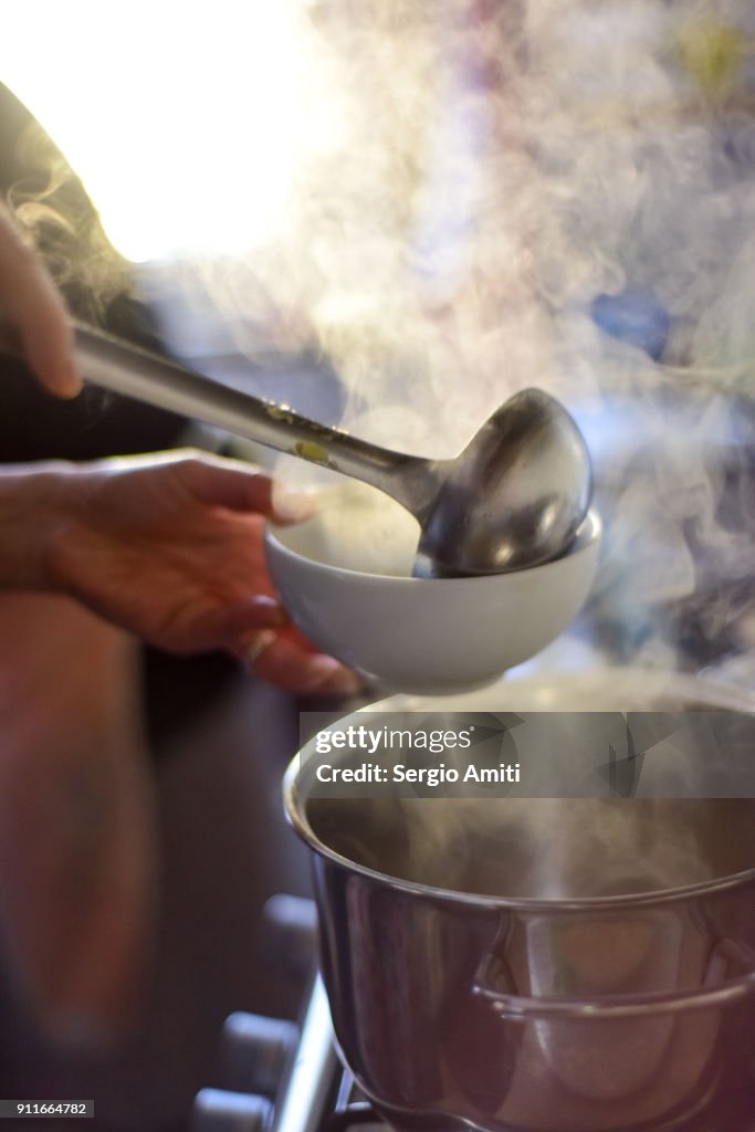 Serving tortellini into a bowl using a ladle