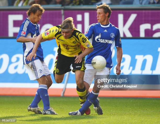 Rafinha and Benedikt Hoewedes tackle Marcel Schmelzer of Dortmund during the Bundesliga match between Borussia Dortmund and FC Schalke 04 at the...