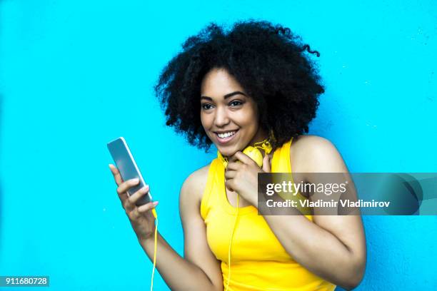 lachende vrouw met gele vest en koptelefoon luisteren van muziek - fashion pretty woman listening music in headphones with smartphone colorful stockfoto's en -beelden