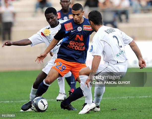 Montpellier midfielder Younes Belhanda vies with Boulogne defender Nicolas Rabuel and midfielder Olubayo Adefemi during their French L1 football...