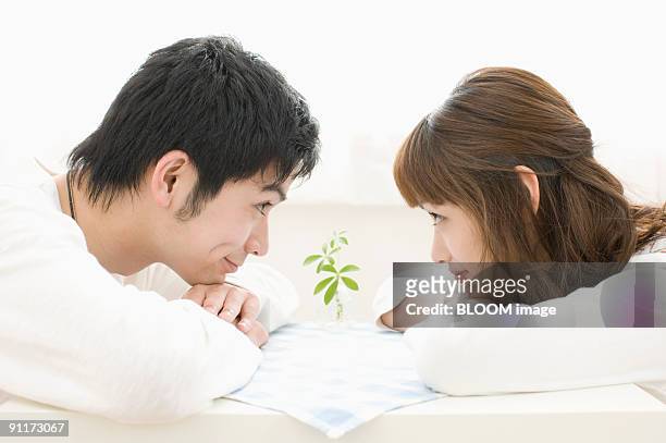 young couple looking at each other, leaning on table - 見つめる ストックフォトと画像