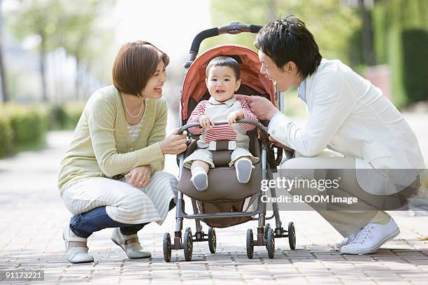 father and mother smiling at baby boy in stroller - かがむ 人 横 ストックフォトと画像