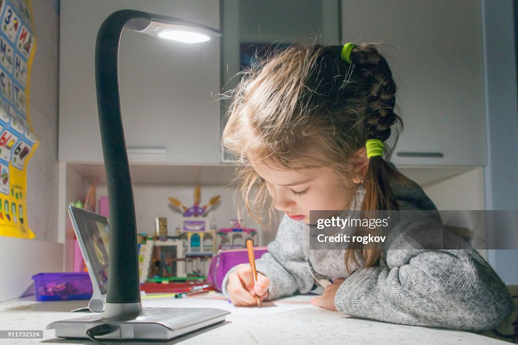 Uitvoering van school lessen laat in de avond bij het licht van een tafellamp.