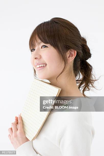 young woman holding book - cabeça inclinada imagens e fotografias de stock