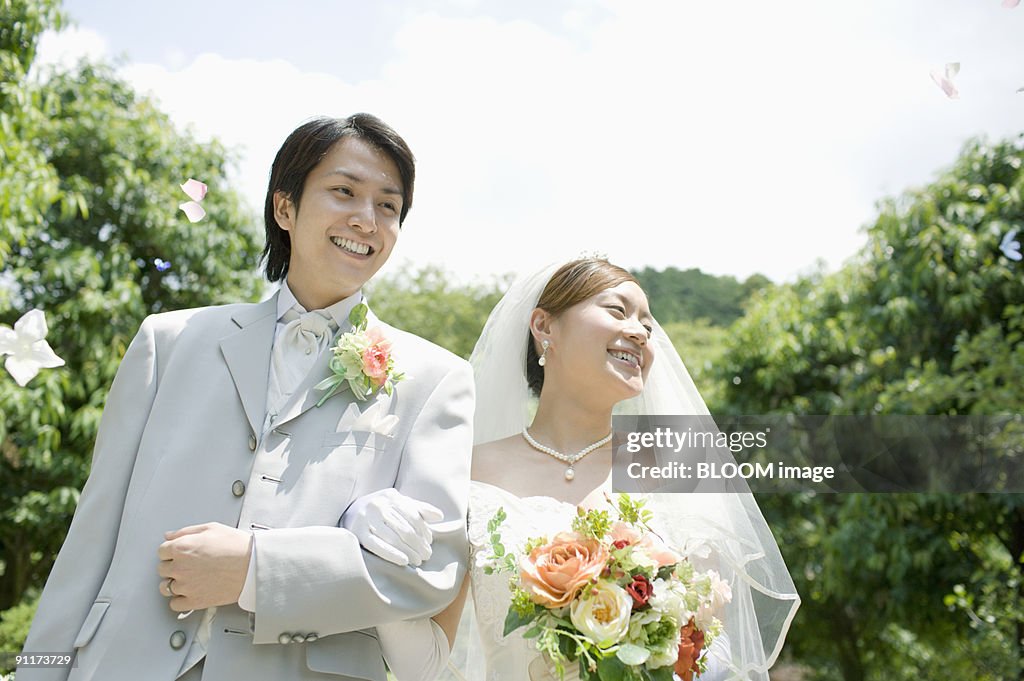 Bride and groom in flower shower, smiling, walking arm in arm