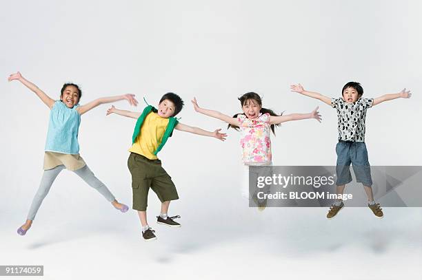 children jumping, outstretching arms, studio shot - jumping casual clothing studio shot stock-fotos und bilder