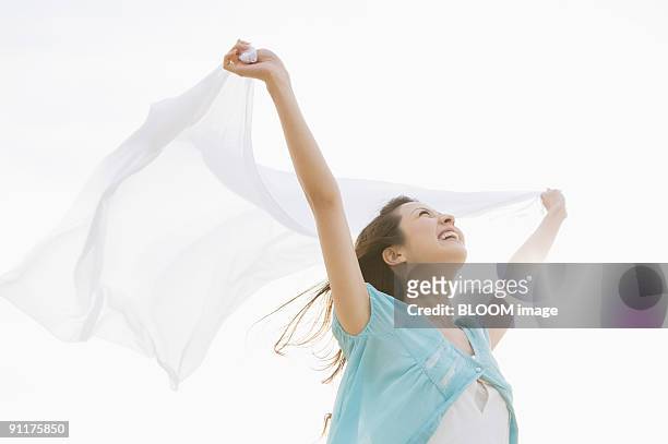 young woman holding a scarf streaming in the wind - ショール ストックフォトと画像
