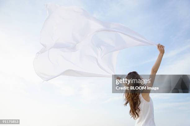 young woman holding a scarf streaming in the wind - woman fresh air photos et images de collection