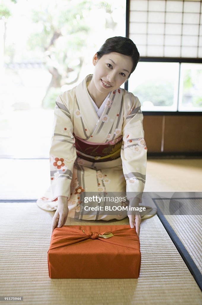 Woman in kimono holding out gift