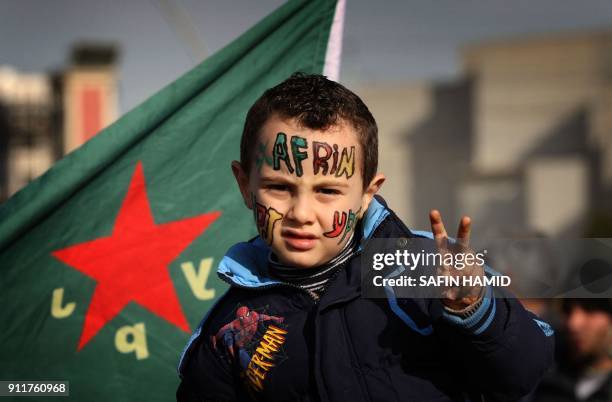 Syrian Kurdish child flashes the sign for victory outside the United Nations office in the northern Iraqi city of Arbil, the capital of the...