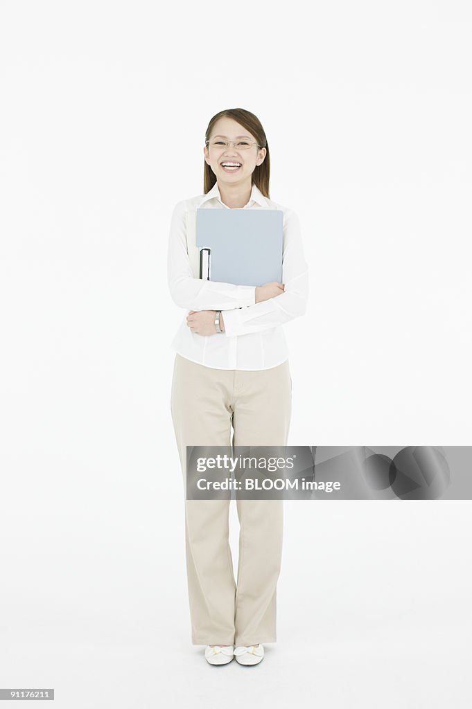 Woman holding file folder, smiling, studio shot