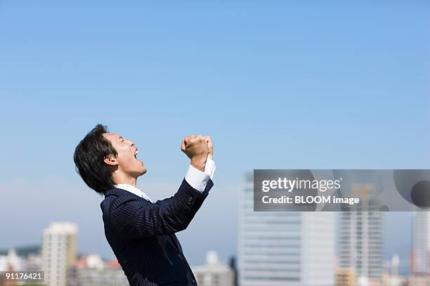 businessman shouting, clenching fists, side view - punching the air stock pictures, royalty-free photos & images