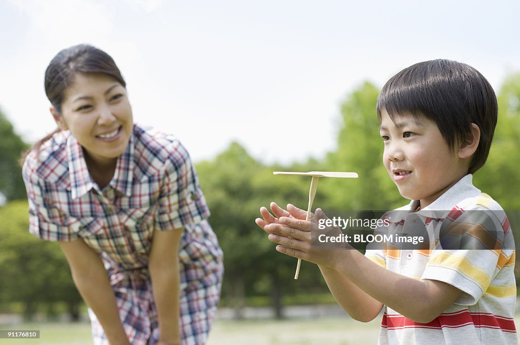 Mother and son playing with propeller-shaped flying toy made of bamboo