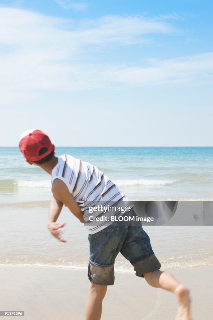 Boy playing on shore, rear view