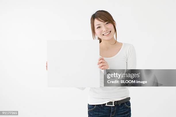 young woman holding white board, studio shot - ボード　持つ　女性 ストックフォトと画像