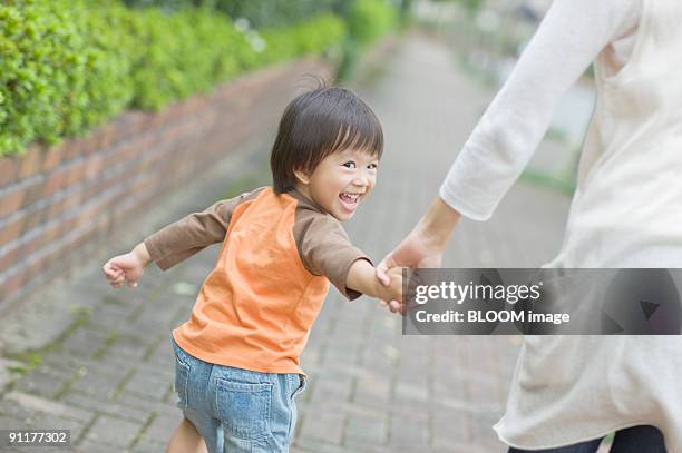 mother and son walking hand in hand - boy looking over shoulder stock pictures, royalty-free photos & images