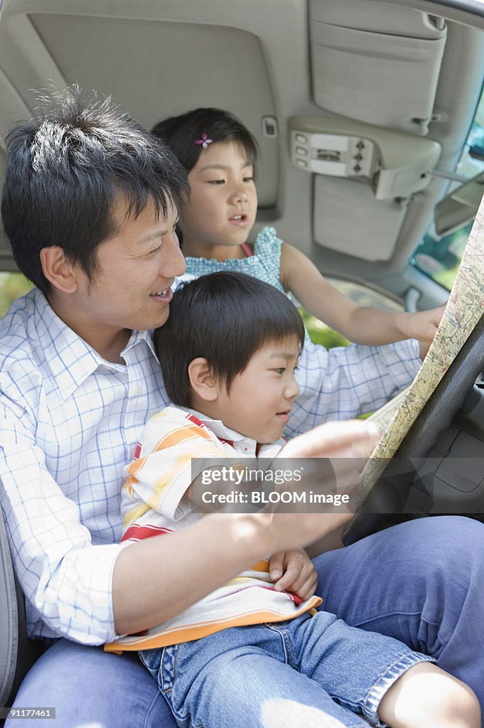 Father and children in car, looking at map