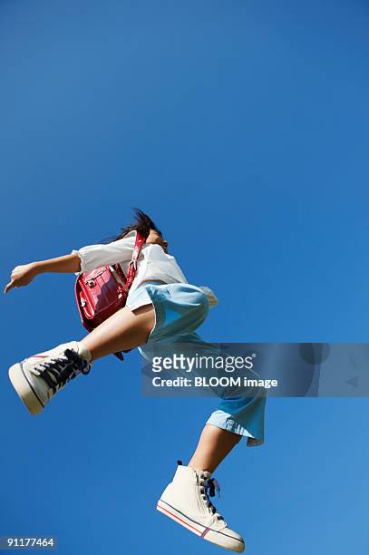 girl with school satchel jumping, low angle view - low angle view stock pictures, royalty-free photos & images