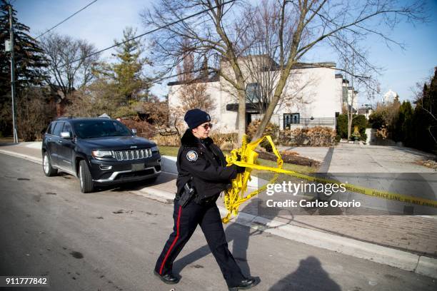 Police officer removes the police tape from the Sherman home Friday morning. Toronto police released the home back to the Sherman family Friday...