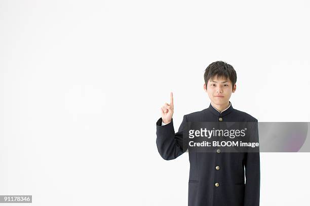 high school student pointing upward, portrait, studio shot - 制服 ストックフォトと画像