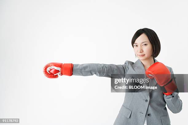 businesswoman wearing boxing gloves - womens boxing fotografías e imágenes de stock