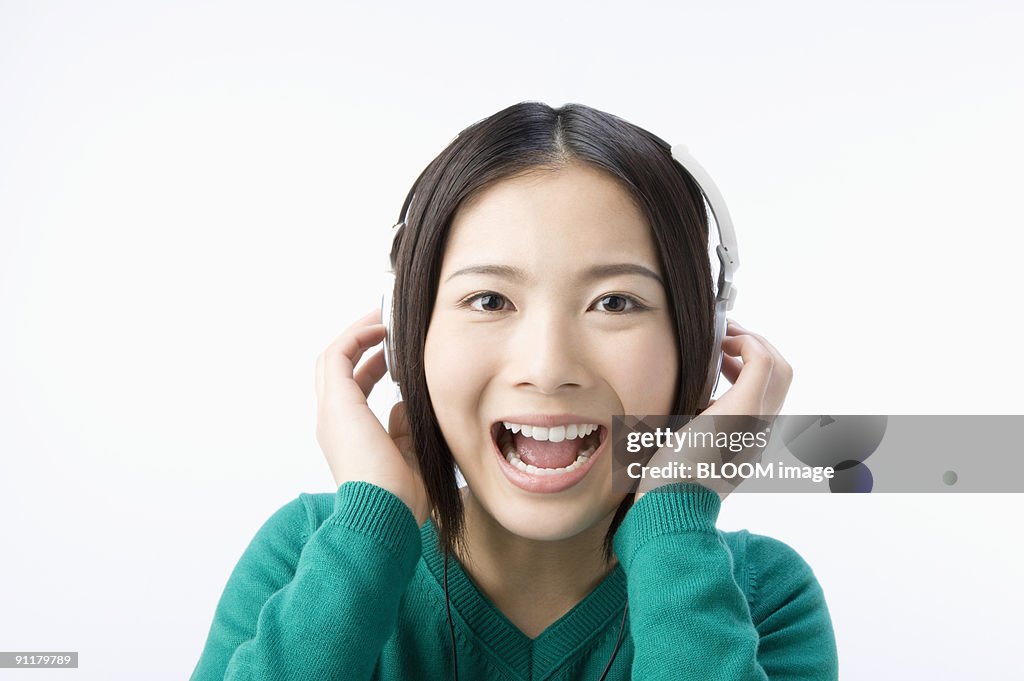 Young woman listening to music with headphones, studio shot
