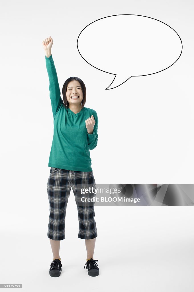 Young woman making pose and speech bubble on wall, studio shot